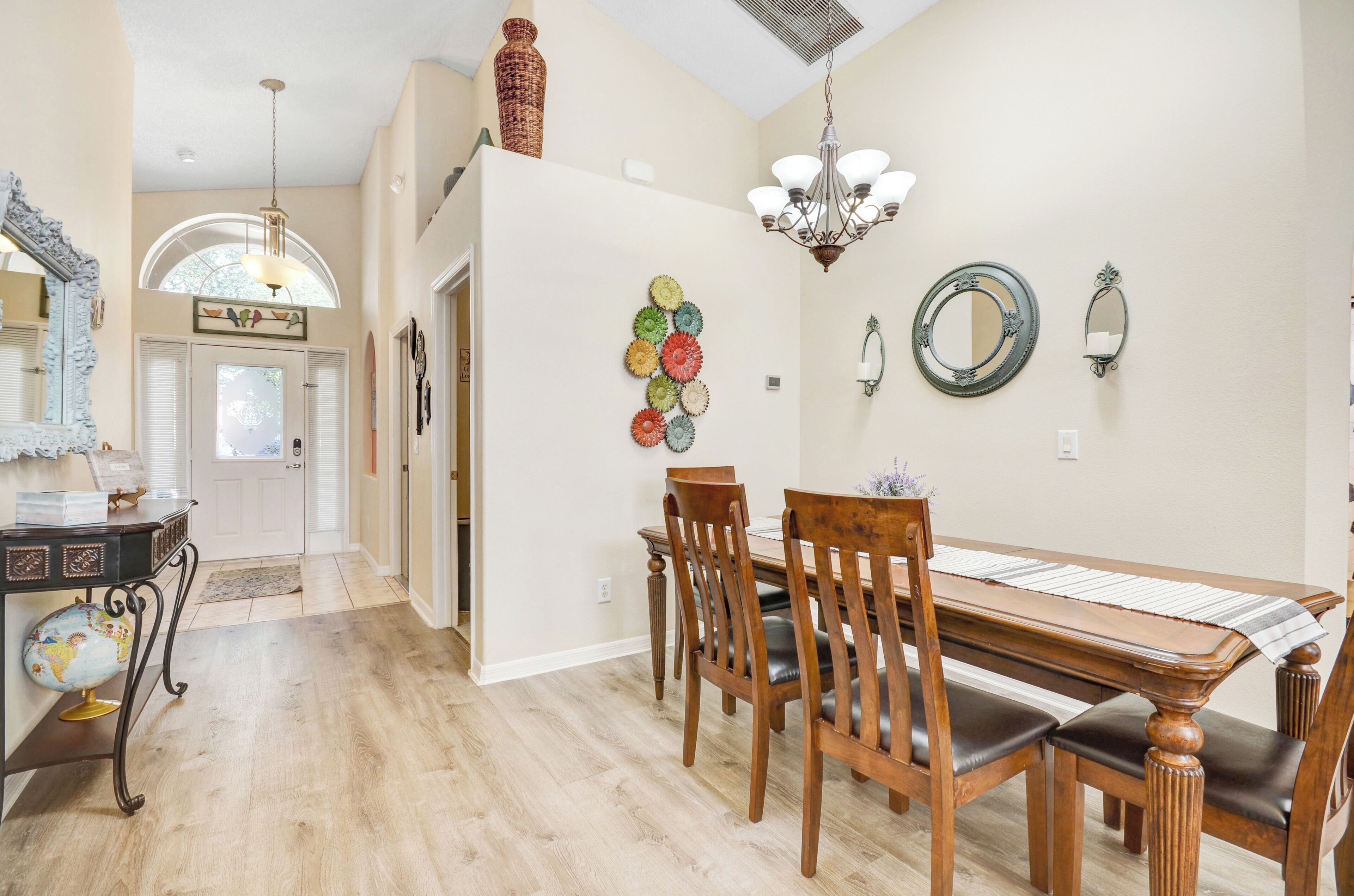 A dining area with a wooden table and chairs, a chandelier, and decorative wall art.