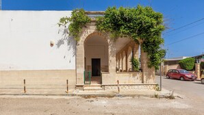A building with a white facade, an arched entrance, and a small garden area with a car parked nearby. - 4005 Villetta Stella by Barbarhouse (Manduria)