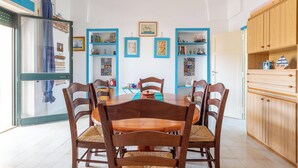 A dining area with a round table, six wooden chairs, and a blue-framed bookshelf. - 4005 Villetta Stella by Barbarhouse (Manduria)
