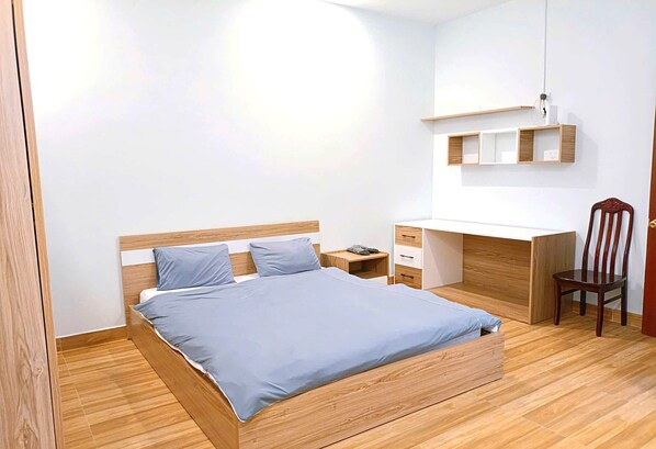 A bedroom with a wooden bed, a desk, and a chair. - OYO 1248 Quyen House (Cam Ly - Da Lat)