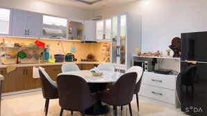 A modern kitchen with a dining area, featuring cabinets, a stove, and a refrigerator. - OYO 1248 Quyen House (Cam Ly - Da Lat)