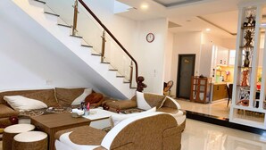 A modern living room with a staircase, a sofa set, a coffee table, and a decorative cabinet. - OYO 1248 Quyen House (Cam Ly - Da Lat)