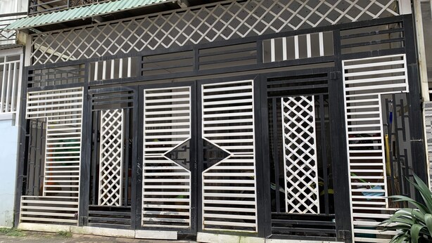 A building with a black and white facade, featuring a central diamond-shaped window and symmetrical shutters. - OYO 1248 Quyen House (Cam Ly - Da Lat)