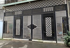 Un edificio con facciata bianco e nero, caratterizzato da una finestra a forma di diamante al centro e persiane simmetriche.