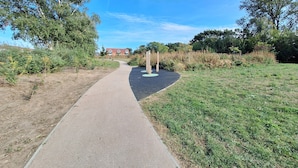 A paved pathway leading to a building with a red roof, surrounded by greenery and trees. - Lodge - Sleeps 2 - Pet Friendly - Parking - Patio (Sidcup)
