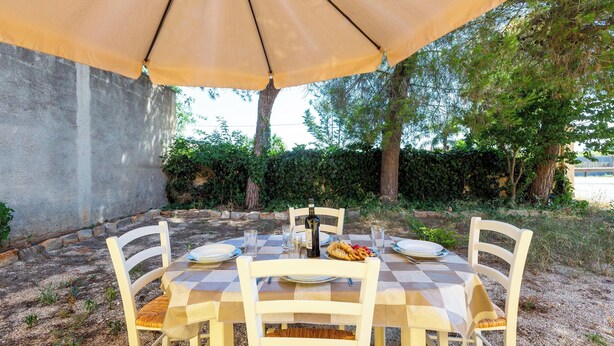 An outdoor dining area with a checkered tablecloth, white chairs, and a large umbrella. - 4087 Cascina Mimì by Barbarhouse (Nardò)