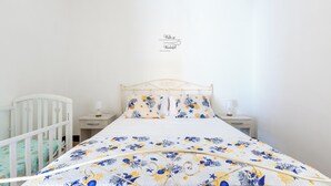 A neatly made bed with floral bedding, a white crib, and a bedside table with a lamp. - 4087 Cascina Mimì by Barbarhouse (Nardò)