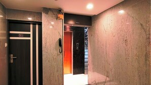 A hallway with a black door marked 403, a phone, and a staircase leading to an elevator. - HOTEL STEAM (Kolkata)