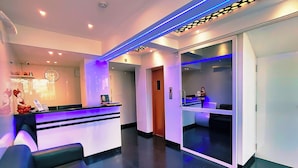 A modern reception area with a reception desk, seating area, and a glass partition. - HOTEL STEAM (Kolkata)
