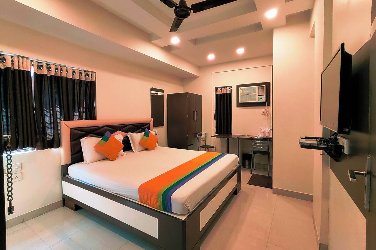 Une chambre d’hôtel équipée d’un lit, d’un bureau, d’une chaise, d’une télévision et d’un ventilateur de plafond.