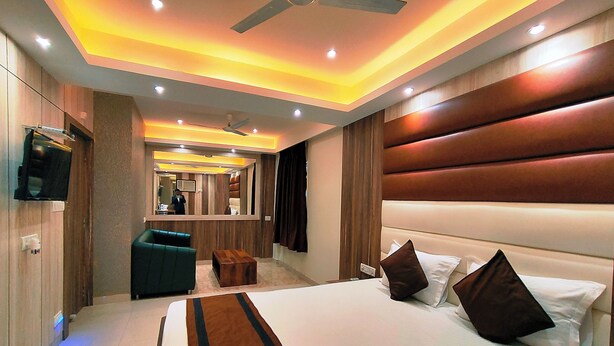 A modern hotel room with a large bed, a seating area, and a television. - HOTEL STEAM (Kolkata)