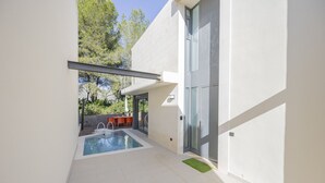 Una casa moderna con piscina, puerta de cristal y patio amoblado.