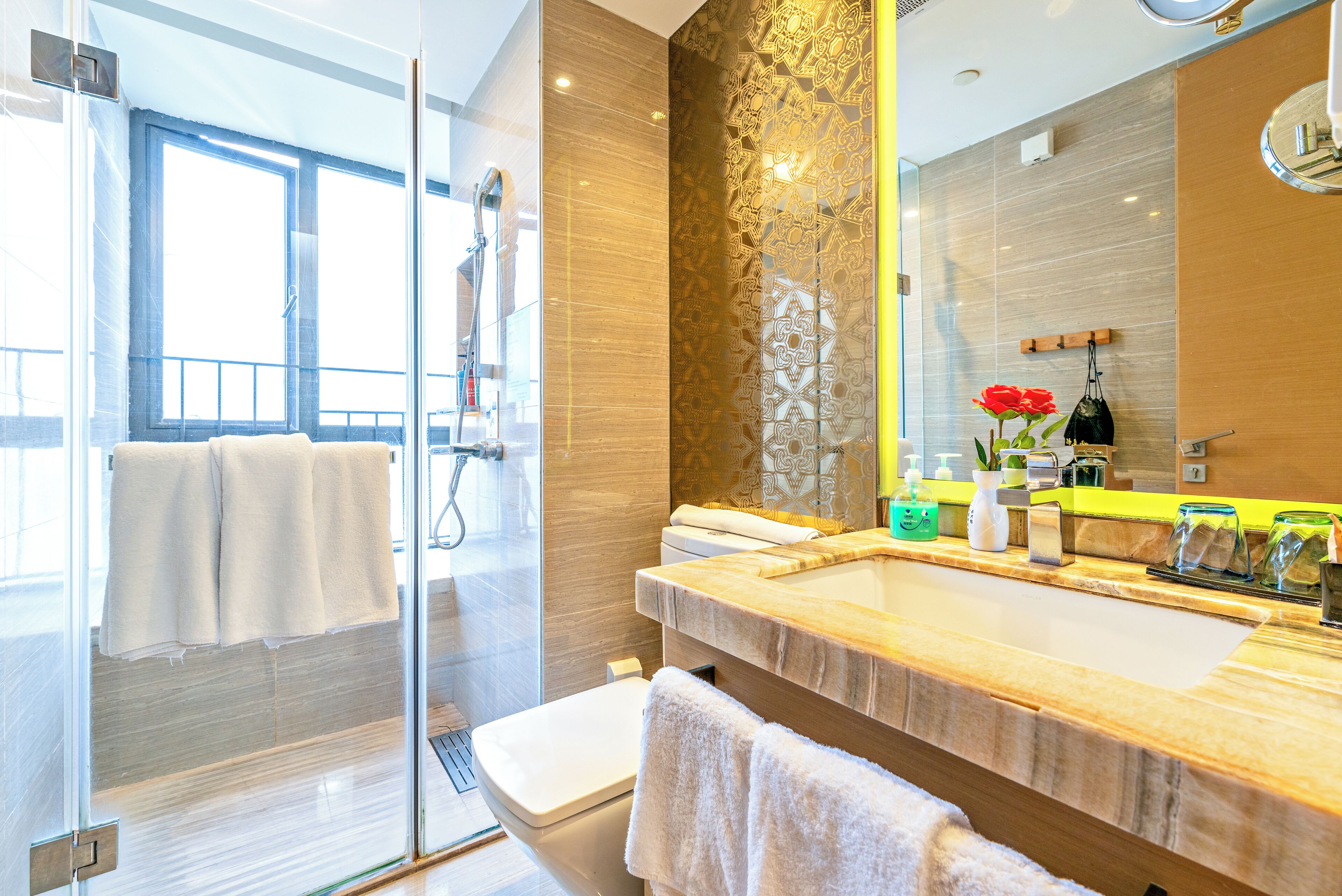 A modern bathroom with a glass shower enclosure, a wooden vanity, and a large mirror.