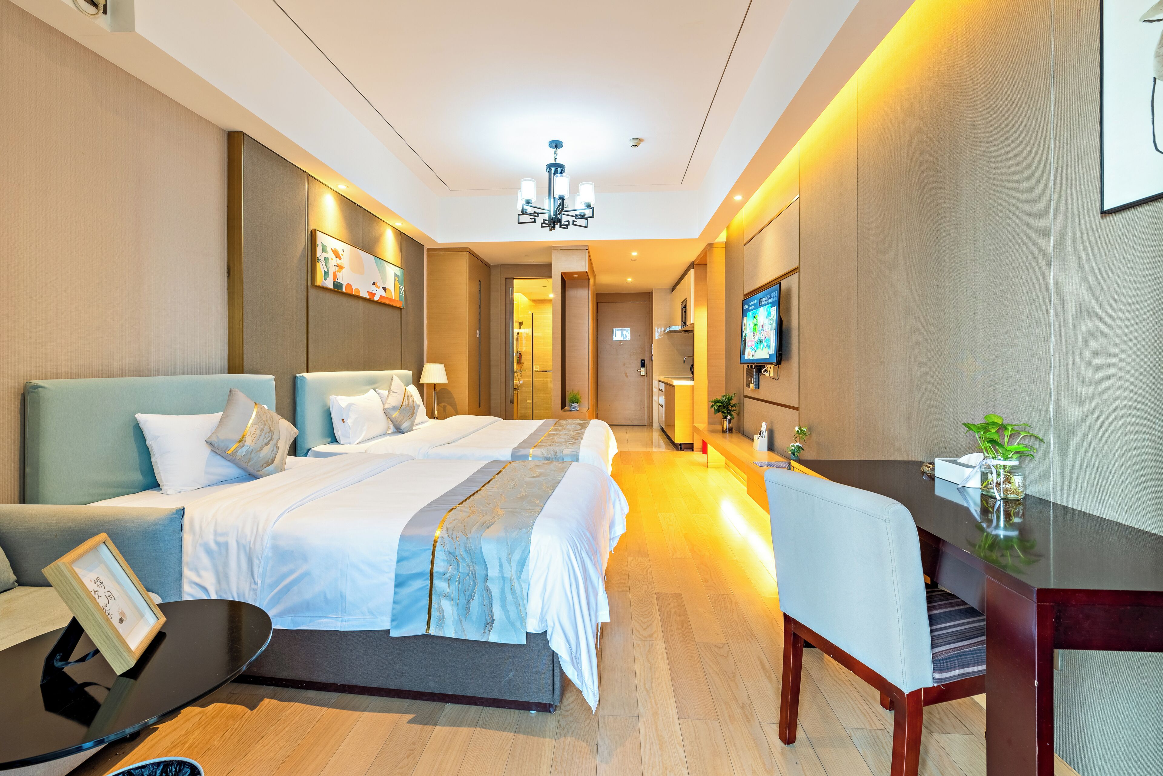 Una habitación de hotel con una cama grande, un escritorio, una silla, un televisor y una pequeña mesa con una planta.