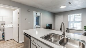 Una cucina moderna con una grande isola, lavello in acciaio inossidabile e lavastoviglie.