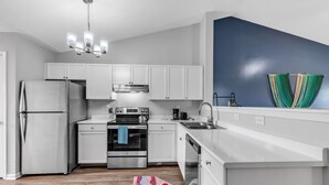 Cocina moderna con armarios blancos, electrodomésticos de acero inoxidable y una pared de acento azul.