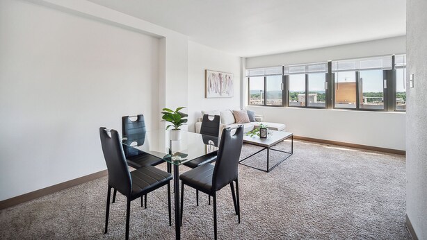 Ein modernes Wohnzimmer mit Essbereich, großen Fenstern und Blick auf die Stadt.