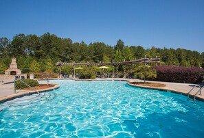 Une piscine à l’eau d’un bleu cristallin, entourée d’une terrasse en bois et de chaises longues.
