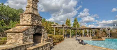 A stone-built outdoor area with a pool, lounge chairs, and a pergola.