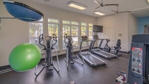 A gym with treadmills, elliptical machines, and a green exercise ball.