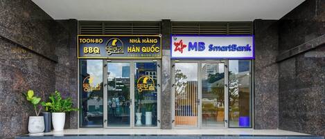 Entrada de un edificio con un restaurante de barbacoa y un SmartBank.