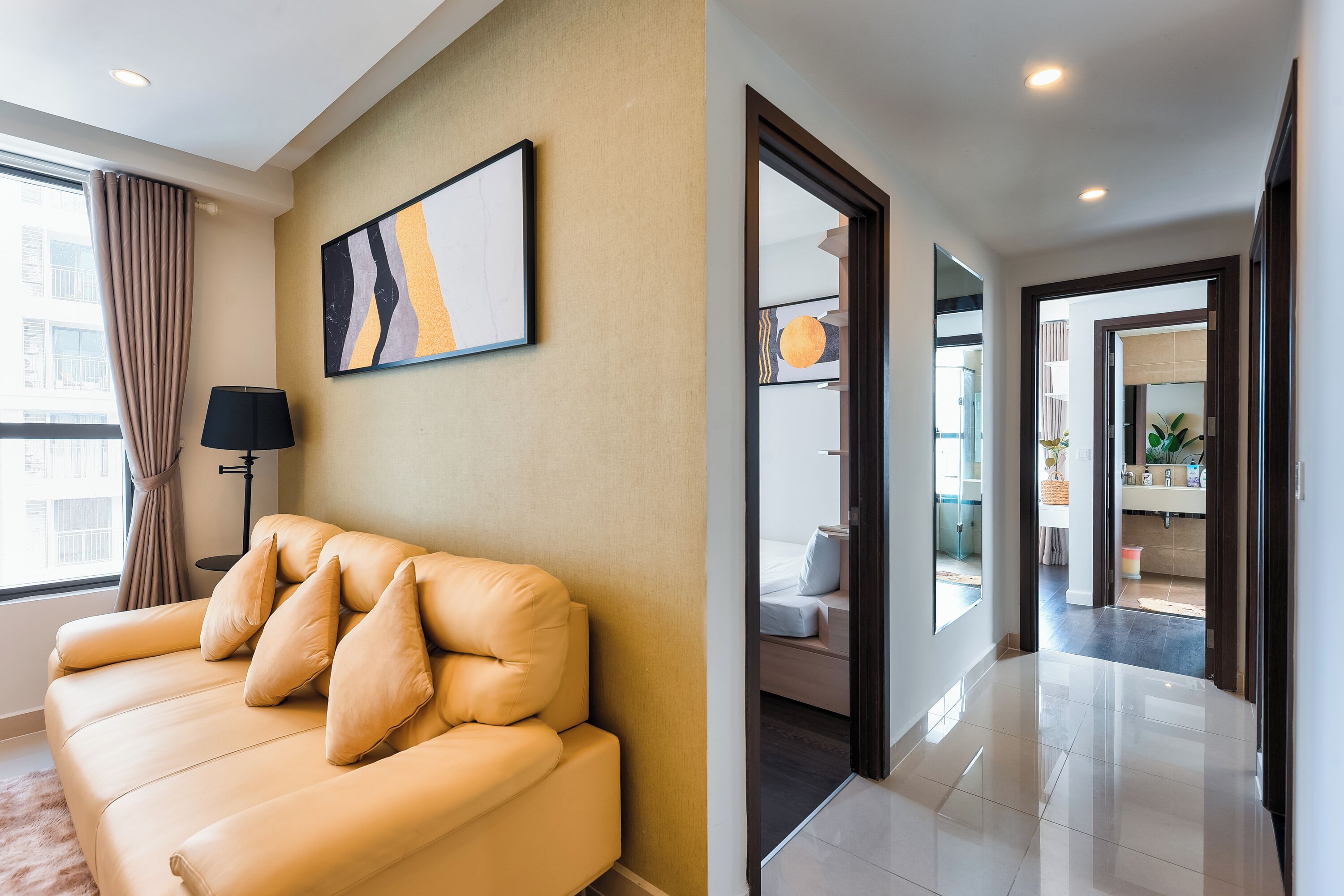 A modern living room with a beige sofa, a floor lamp, and a large abstract painting on the wall.