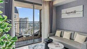 A modern living room with a grey sofa, a coffee table, and a view of a cityscape through a large sliding glass door. - S Lux Apartment (Ho Chi Minh City)