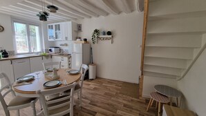 Una cocina moderna con armarios blancos, una mesa de comedor para cuatro personas y suelo de madera.