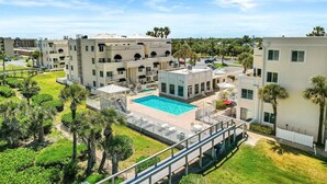 A resort with multiple buildings, a swimming pool, and palm trees.
