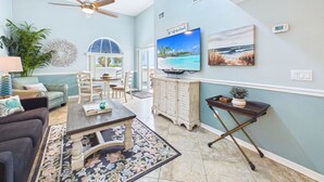 A spacious living room with a ceiling fan, a television, a dining area with a view, and a large window.