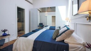 A bedroom with a large bed, a wardrobe, a mirror, and a bedside table with a lamp.