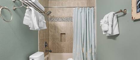 A bathroom with a toilet, bathtub, and shower curtain.