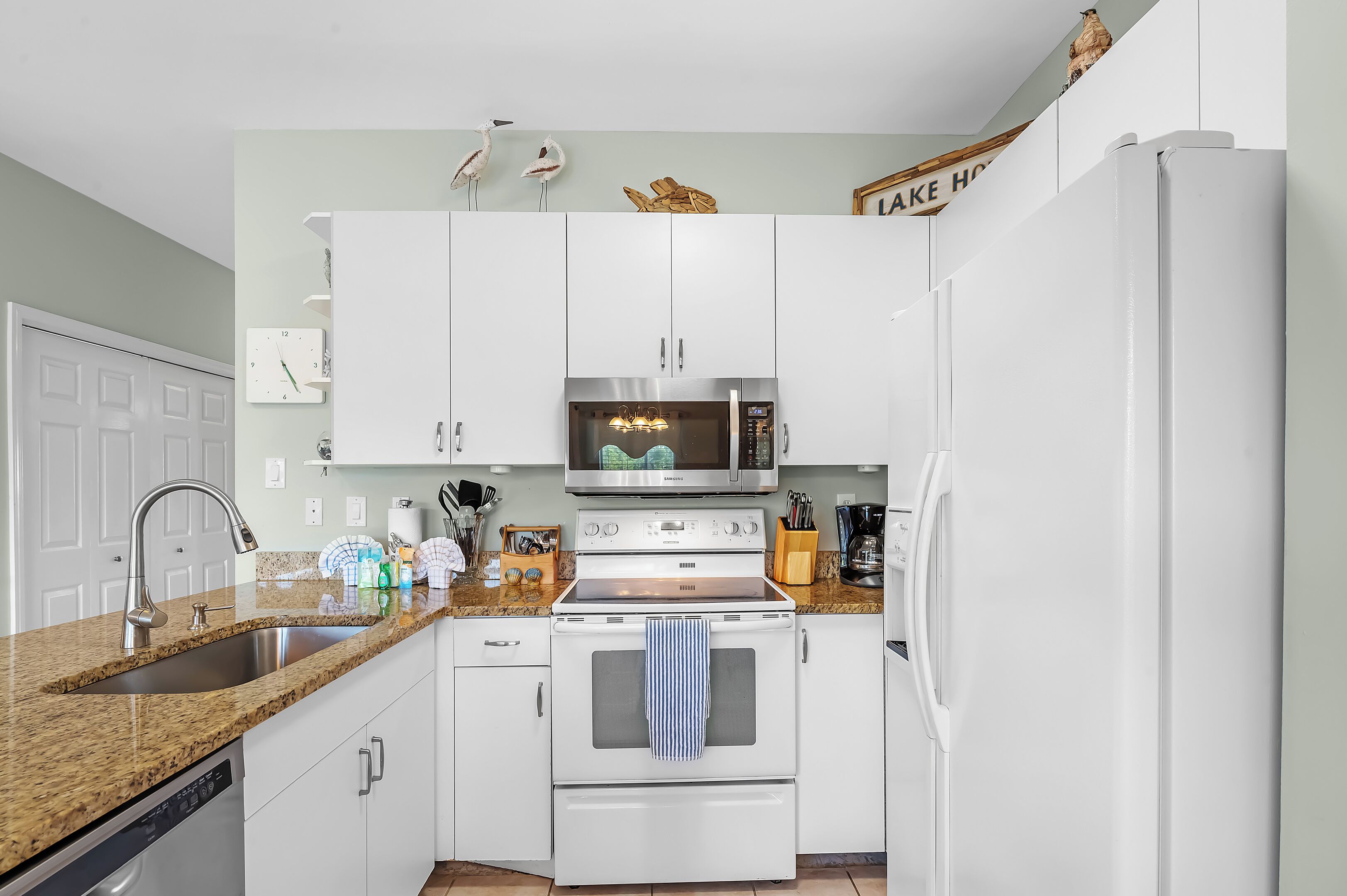 A kitchen with white cabinets, a stainless steel microwave, a built-in oven, and a refrigerator.