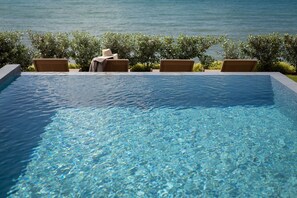 A clear blue pool with four chairs and a hat on one of them, surrounded by greenery. - Villa Koh-I-noor (Le Diamant)