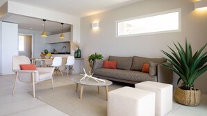 A modern living room with a sofa, armchairs, a coffee table, and a dining area with chairs and a table. - Villa Koh-I-noor (Le Diamant)