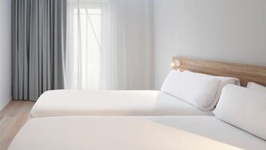 Ein Hotelzimmer mit Doppelbett, Holz-Kopfteil und großem Fenster mit transparenten Vorhängen.