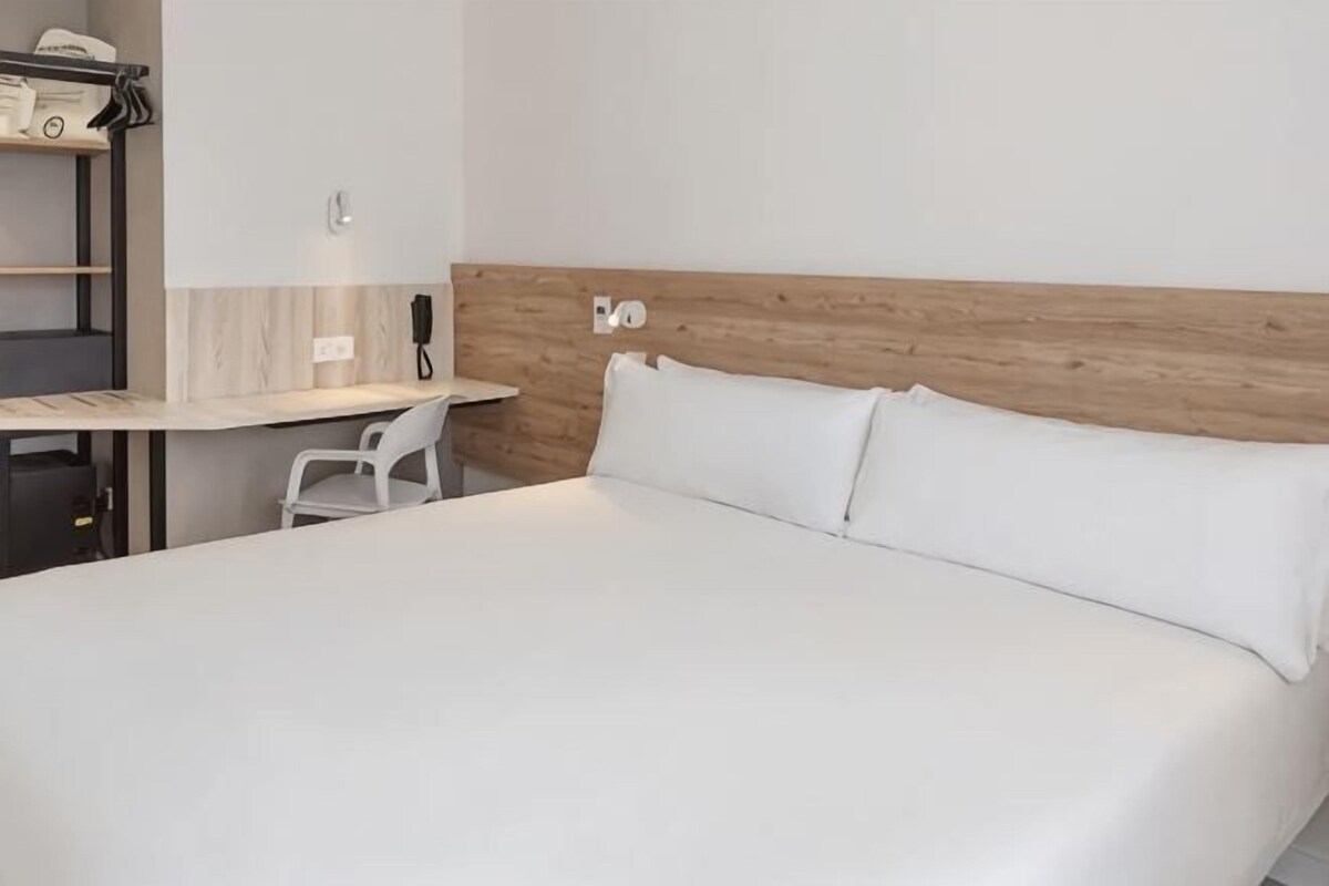 Una habitación de hotel con una cama, un escritorio y una silla.
