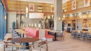 Ein geräumiges Restaurant mit hohen Decken, Holzböden und einer Mischung aus Sitzgelegenheiten, darunter Tische, Sitzecken und eine rote Couch.