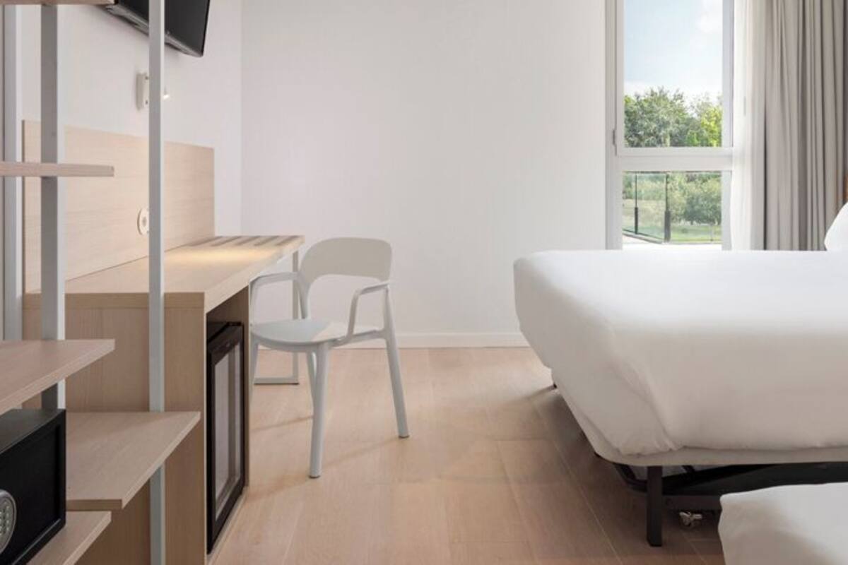 Una habitación de hotel con cama, escritorio, silla y televisor.