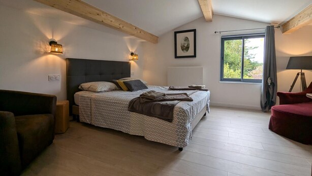 Une chambre à coucher avec un lit, deux lampes de chevet, une fenêtre, une chaise et une lampe.