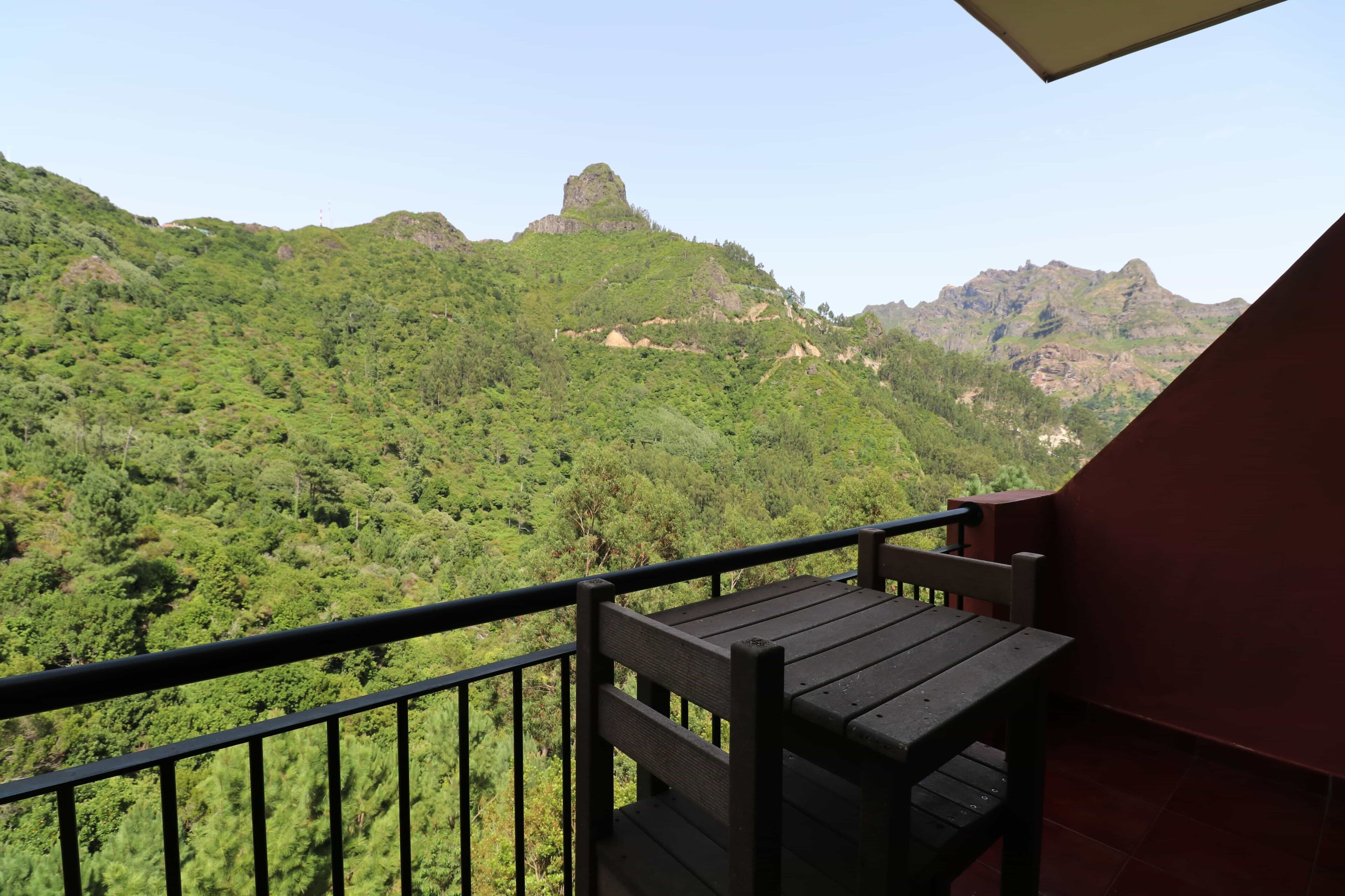 Un balcón con banca de madera con vista a un paisaje montañoso.