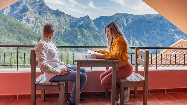Two people sitting at a table with a mountain view. - Valley View Hotel Encumeada (Ribeira Brava)