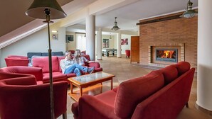 A spacious living area with red sofas, a coffee table, and a fireplace. - Valley View Hotel Encumeada (Ribeira Brava)