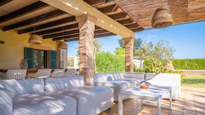 A covered outdoor seating area with white sofas and a white table, surrounded by greenery and a clear sky. - L'ERESTA - Wonderful villa with private pool and Free Wifi (Pollença)