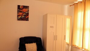 Una stanza con una poltrona in pelle nera, un armadio bianco e un quadro appeso al muro.