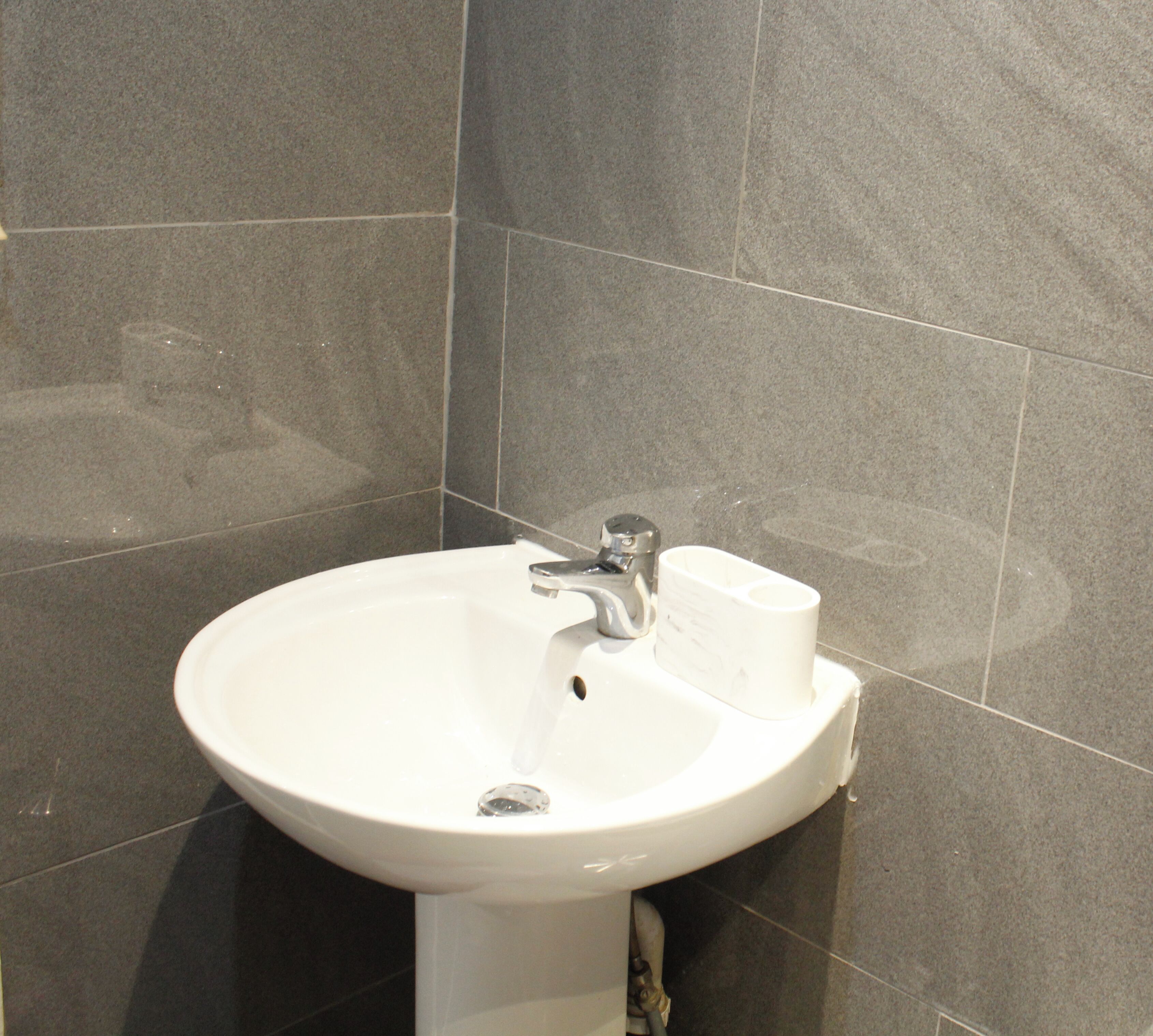 A white bathroom sink with a modern faucet, a soap dispenser, and a towel holder.