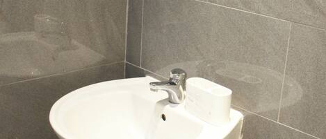 A white bathroom sink with a modern faucet, a soap dispenser, and a towel holder.