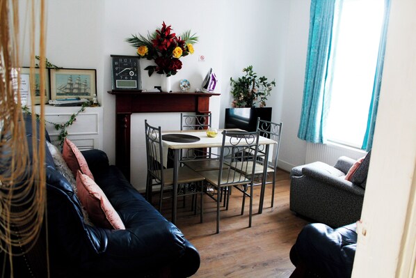 Un salon comprenant un canapé, une table à manger avec des chaises, une cheminée et un téléviseur.