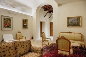 Un'ampia stanza con soffitto alto, un tappeto rosso decorato e un arredo che combina elementi moderni e classici, tra cui divani e poltrone.