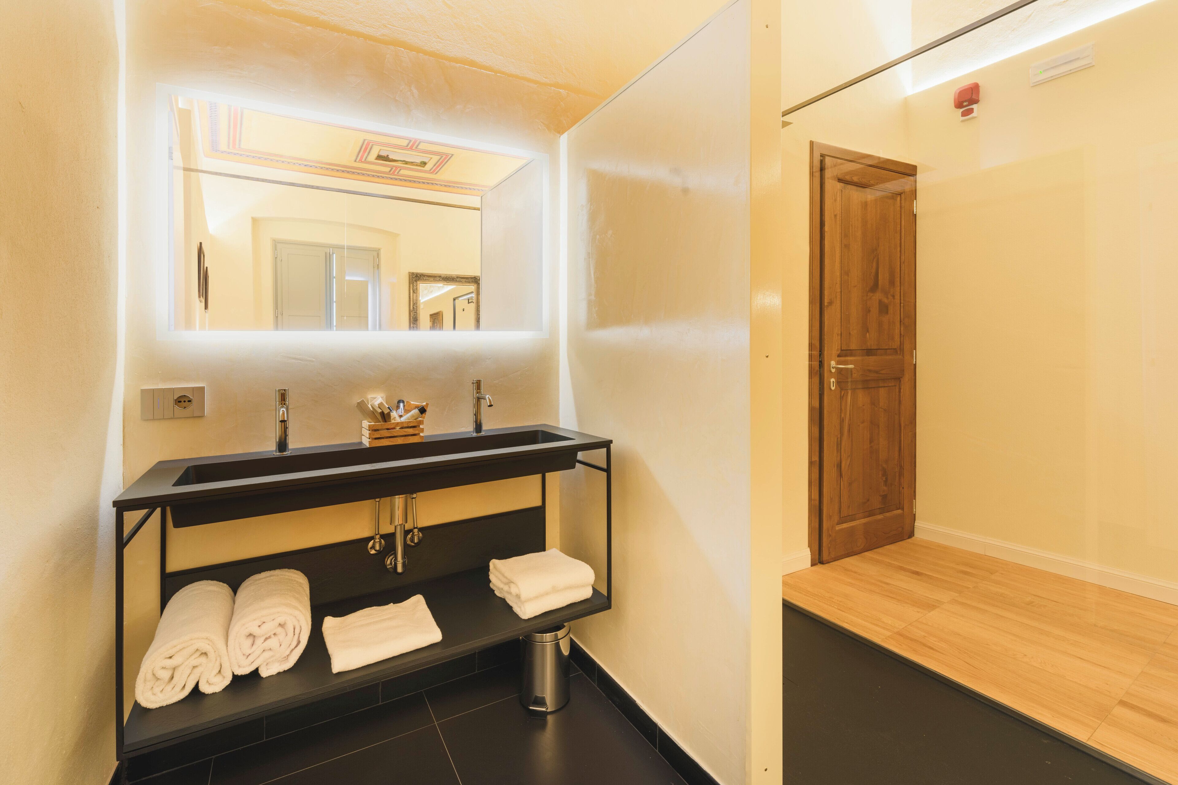 Un baño moderno con un mueble de tocador negro, un espejo y una puerta de madera.